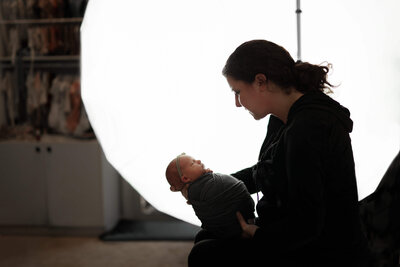 Newborn Photographer soothing a swaddled newborn baby in a photography