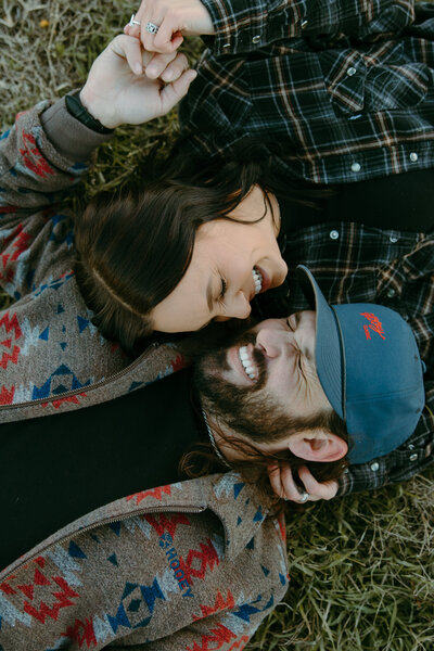 A engaged couple face to face smiling and laughing laying down in Austin Texas
