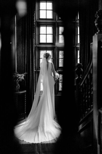 black and white photo of bride looking out the window