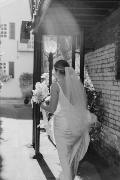 Modern and chic black and white downtown bridals of bride walking by brick building wearing long veil.