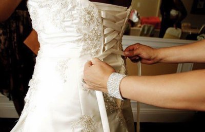 Woman lacing back of wedding dress
