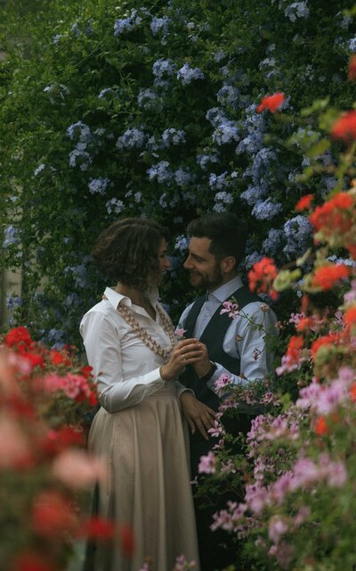 Couple sharing a tender moment in the lush Drummond Castle Gardens greenhouse, surrounded by vibrant greenery and timeless romantic charm