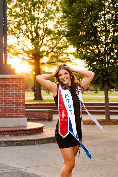 Alpha Omicron Pi and Dance Team graduation photos outside of the Middle Tennessee State University library during golden hour wearing black dress and graduation stoles