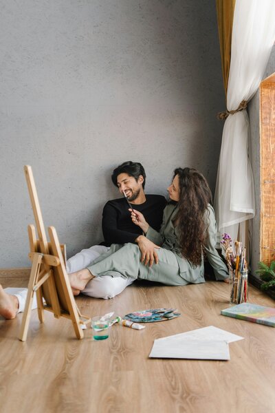 Couple embracing a new experience, painting together and creating memories in a cozy setting.