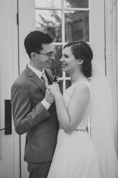 Black and white photo of groom and bride holding hands and smiling at each other  by Iowa City wedding photographer Sabrina Wilham