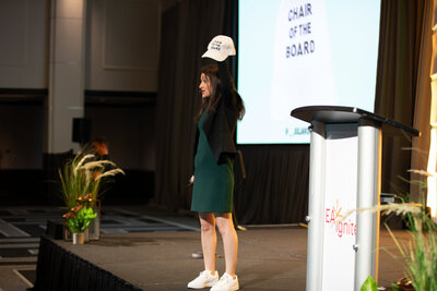 Julia Korn Speaking on Stage with hat