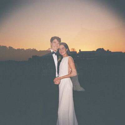 Bride and groom hug and hold hands and look at the camera
