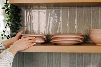 Woman touching plates on a kitchen shelf