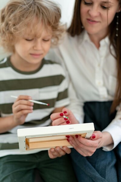 A teacher is helping a young male student with writing