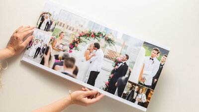 An heirloom wedding album opened as someone is turning the page of a couple's wedding ceremony photos.