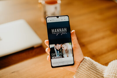 Holding phone with wedding photographer website on screen