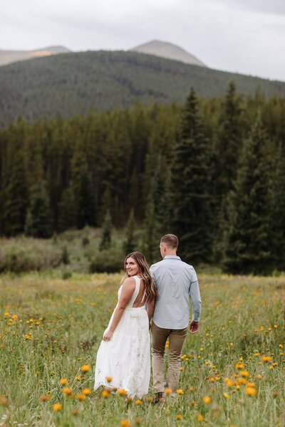 mountain engagement photos in Colorado spring, couple walking through wildflowers