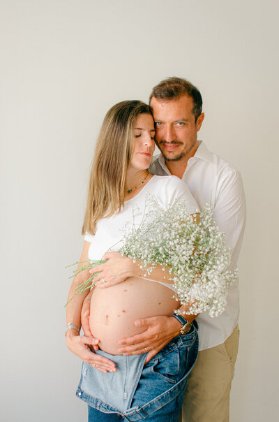 Woman with jean overalls and a white tee shirt during a maternity photoshoot. 