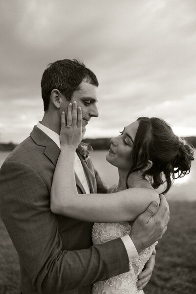 A couple who eloped at Officers Gulch Pond in Colorado, facing away from the camera, sharing a kiss with a stunning lake in front of them and mountains in the background, capturing the beauty of their intimate moment in nature.