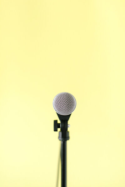 An image of a podcast microphone with a yellow backdrop as an image for Systems and Workflow Educator Dolly DeLong Education Website