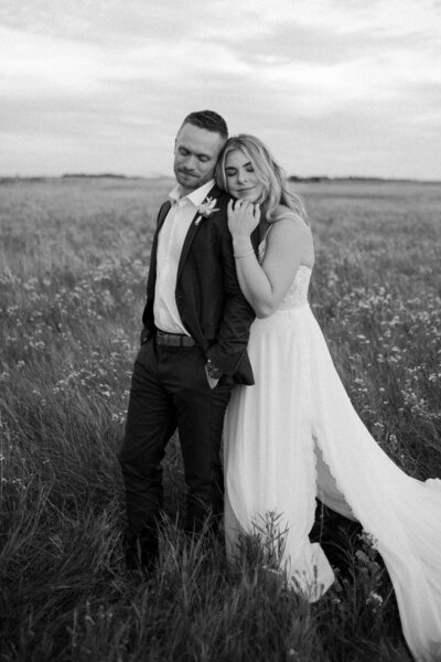 black and white image bride and groom embracing in field