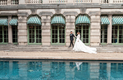 groom holds his brides hand and guides her along the terrace of the Anderson House in Washington, D.C.