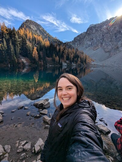 red headed girl smilng in front of Washington Alpine Lake during larch season