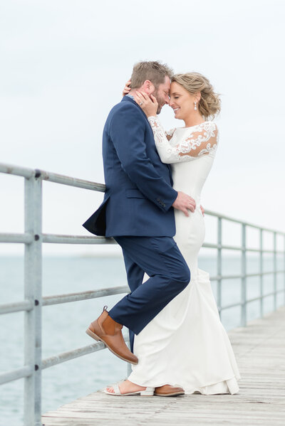 couple embracing each other while leaning against railing on boardwalk on Lake Huron 