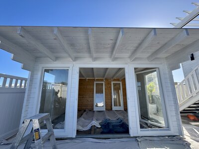 Wooden pool house with large glass windows being renovated