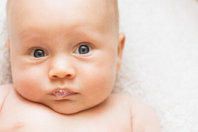a baby with blue eyes blows bubbles
