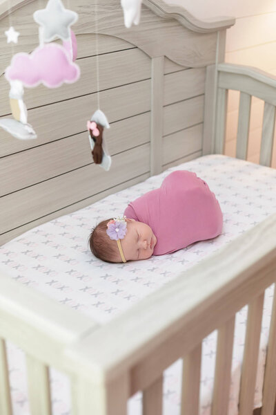 A baby girl in her crib during her NOVA newborn photo session.