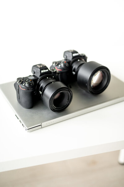 Shot of both Kala and Reg's camera laying on top of a laptop on a white background.