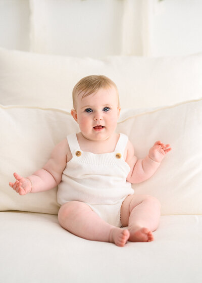 Adorable little girl sitting on a couch smiling at the camera