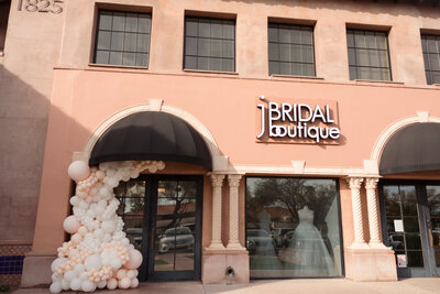 The front entrance of J Bridal Boutique. With two entrance doors and a large display window with wedding dresses on display.