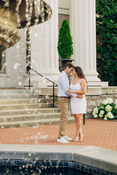 Couple embracing each other near fountain during their engagement session at Belmont University