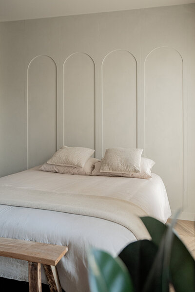 Sfeervol bed in dachtlicht Studio Laurant, geplaatst tegen een muur met vier elegante bogen.