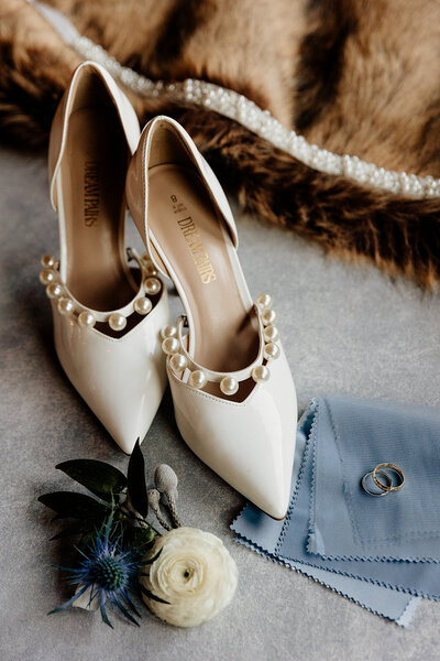 Pearl-beaded bridal heels in a flatlay with navy and slate blue wedding accessories.