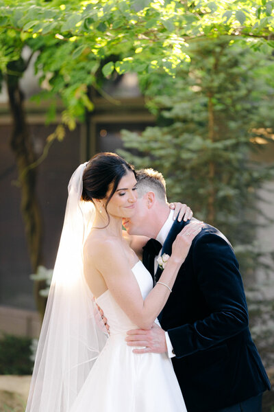Groom giving a kiss to his bride on her neck at the Dallas Arboretum