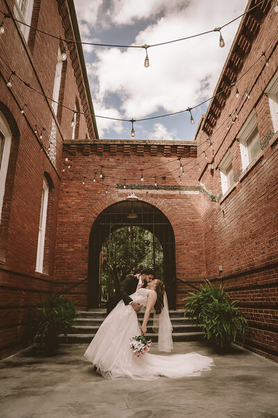 newlyweds dip and kiss brick arch