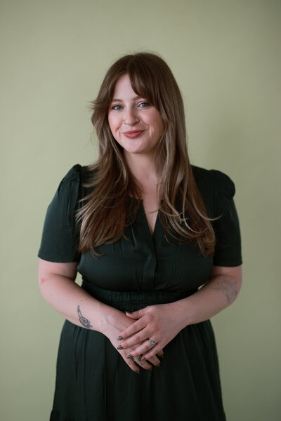woman smiling wearing green dress in front of green backdrop