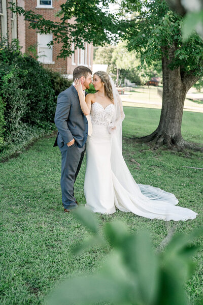 Bride and groom share a romantic moment under a tree. A dreamy wedding portrait by Jackson Ms Wedding Photographer.