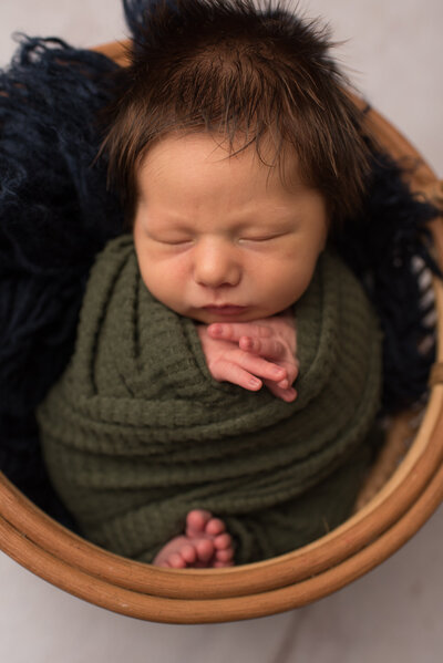 Baby boy wrapped in green wrap on blue fur