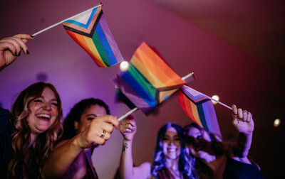 Celebratory moment with friends waving rainbow pride flags in a dimly lit room