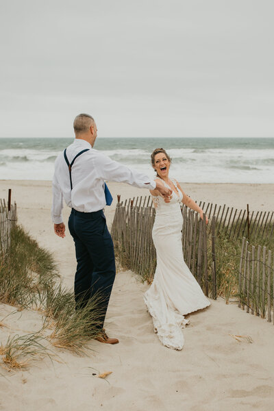 bride and groom holding hands on the sand