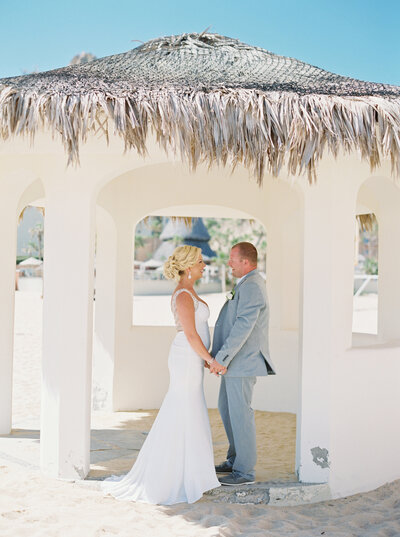 bride and groom under awning in sunny cabo san lucas