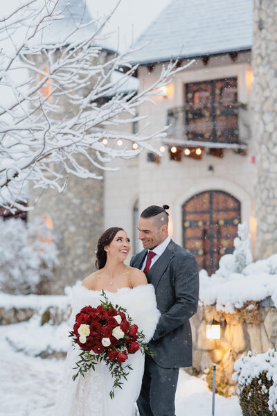 Bride and Groom stand in front of  a snow covered castle