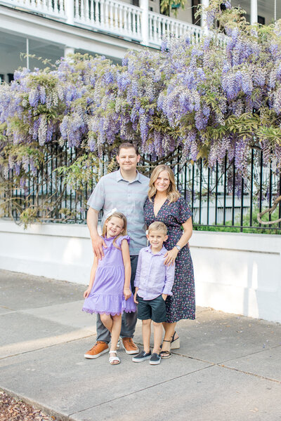 Family of four poses in front of lilac garden in White Point Garden.