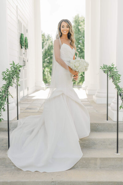 Woman standing in wedding dress holding bouquet for bridal portraits