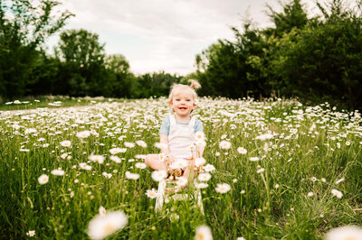 Springfield MO maternity photographer captures pregnant mom kneeling in field holding belly