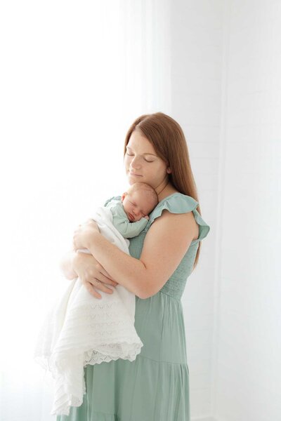 7 day old newborn boy wrapped in a blue swaddle with fingers out in a bamboo basket in Savannah, Ga