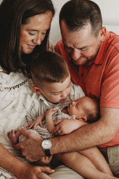 Family posing with newborn baby for newborn photo session.
