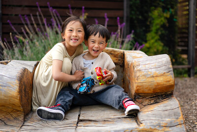 Big sister and younger brother hugging and laughing on a rustic wooden bench — Bay Area Photographer Services - Ellobelle Photography Family Photographer