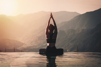 a women doing yoga in the water in front of mountains