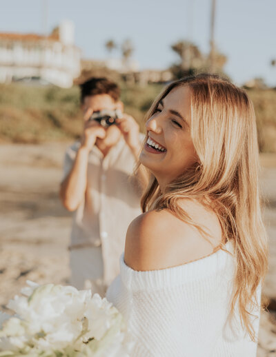 A blonde girl laughs while her partner takes a picture of her.