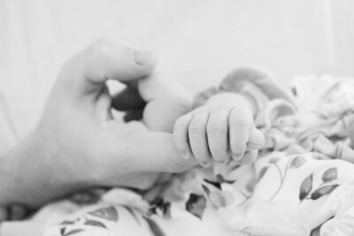 Black & White photo of baby holding parent finger